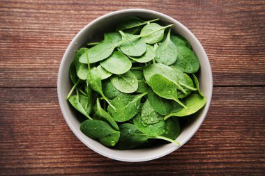 Üzerinde kahverengi ahşap masa kase su damlaları ile ıspanak yaprakları