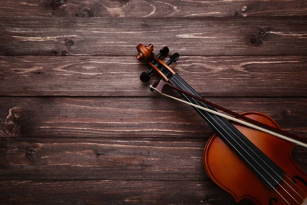 Violin with bow on brown wooden table