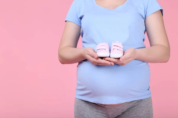 Zwangere Vrouw Houden Babyslofjes Roze Achtergrond — Stockfoto