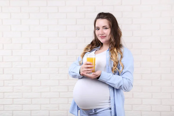 Vacker Gravid Kvinna Med Apelsinjuice Glas Tegel Vägg Bakgrund — Stockfoto