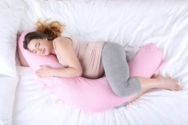 睡在床上的粉红色枕头的年轻孕妇 — 图库照片