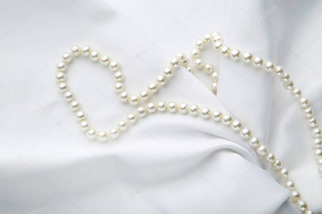 Pearl necklace on white satin fabric