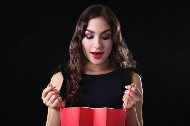 Siyah zemin üzerine kırmızı alışveriş çantası ile mutlu kadın