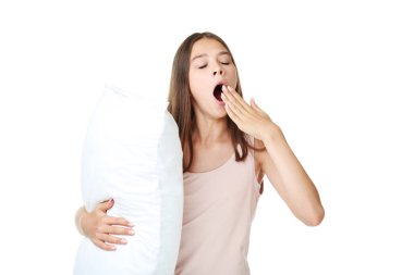 Esneme kız yastık beyaz arka plan üzerinde tutan