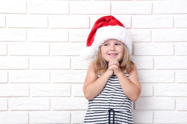 Beyaz tuğla üzerinde santa şapkalı küçük kız duvar arka plan