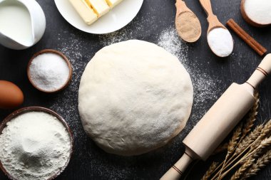 Un ve siyah ahşap yüzey üzerinde oklava ile çiğ hamur