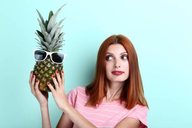 Ananas güneş gözlüğü ile nane arka planda tutan genç redhaired kadın