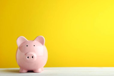 Pink piggy bank on yellow background