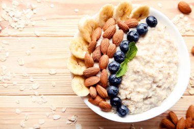 Çilek ve kahverengi ahşap masa üzerinde kase fındık ile yulaf ezmesi