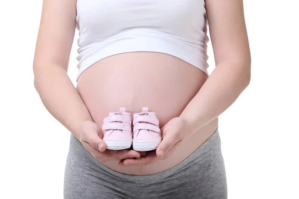 赤ちゃんの靴白い背景の上に保持している妊娠中の女性 — ストック写真