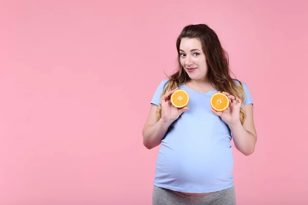 Hermosa Mujer Embarazada Con Fruta Naranja Sobre Fondo Rosa —  Fotos de Stock