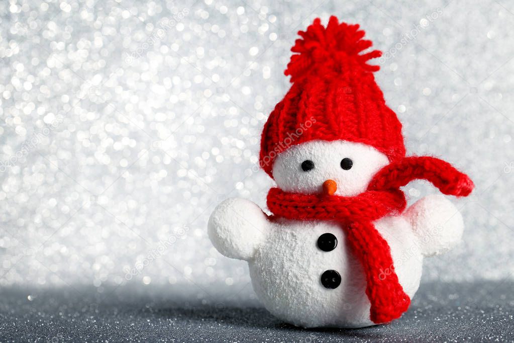 Small snowman toy on silver lights background