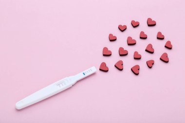 Pregnancy test with red hearts on pink background clipart
