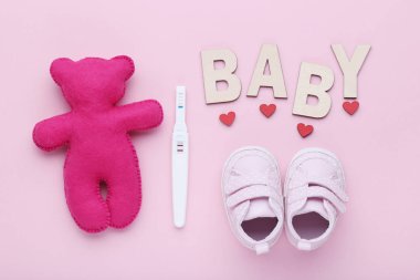 Hamilelik testi ile bebek çizme ve pembe bir arka plan üzerinde yumuşak oyuncak