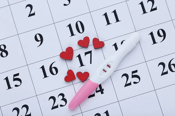 赤いハートの紙のカレンダーの妊娠検査 — ストック写真