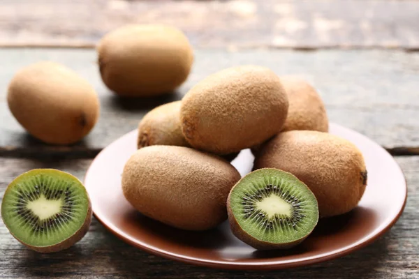 Bütün ve yarıya kivi meyve plaka üzerinde ahşap masa