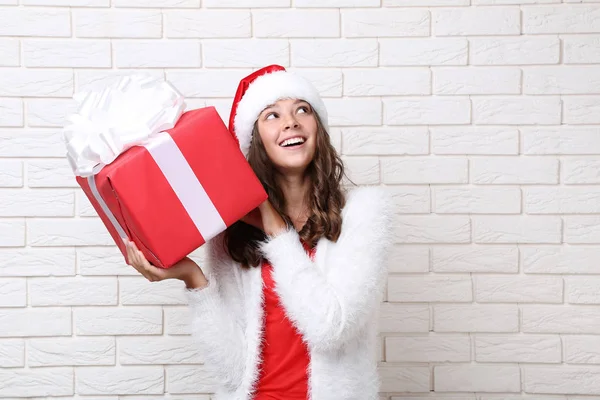レンガ壁の背景にギフト ボックスを保持サンタ帽子で十代の少女 — ストック写真