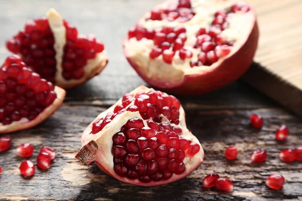 Sulu parçalarını olgun nar gri ahşap yüzey üzerinde