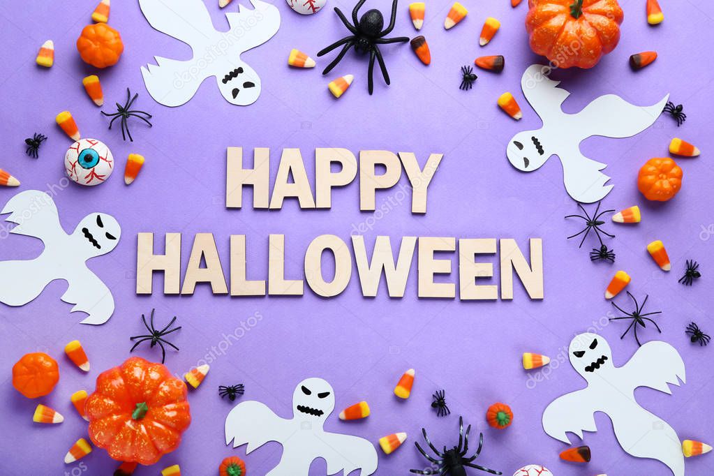 Inscription Happy Halloween with candies and paper decorations on purple background