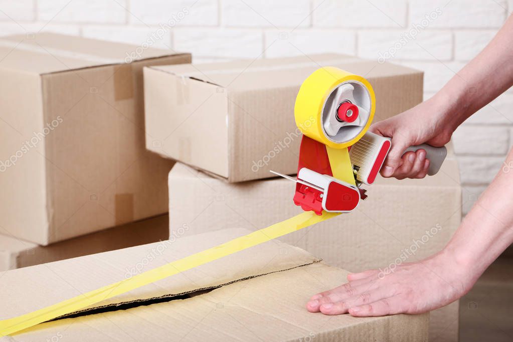 Female hands packaging cardboard box with dispenser