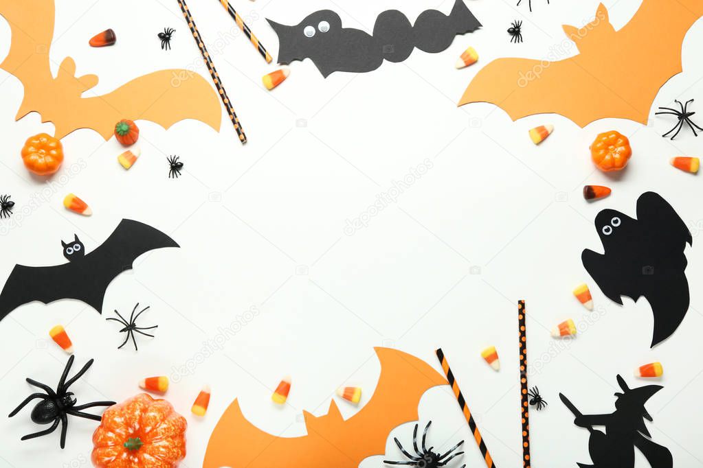 Halloween candies with paper decorations on white wooden background