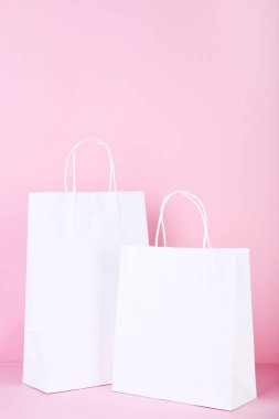 Pembe bir arka plan üzerinde beyaz kağıt poşetler