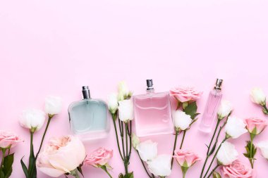 Çiçekli pembe bir arka plan üzerinde parfüm şişeleri
