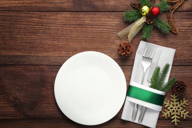 Ahşap masa üzerinde beyaz plaka ve Noel süslemeleri ile mutfak bıçakları