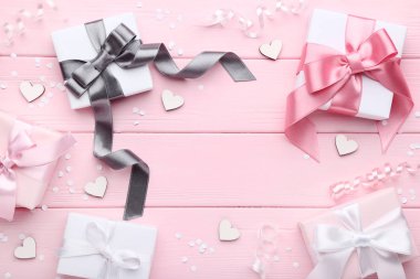 şeritler ve pembe ahşap arka plan üzerinde beyaz kupa ile renkli hediye kutuları