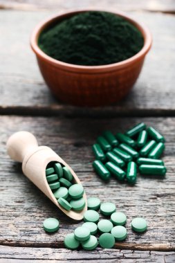 Spirulina toz ve tabletler üzerinde ahşap arka plan gri