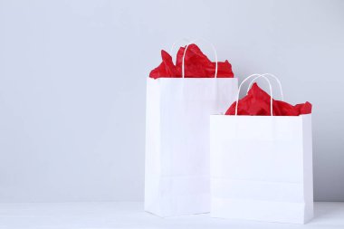 Gri arka plan üzerinde kırmızı kağıt ile beyaz alışveriş torbaları