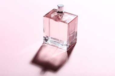 Pembe bir arka plan üzerinde gölge ile parfüm şişesi