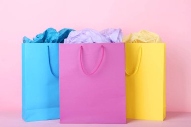 Kağıt üzerinde pembe bir arka plan ile renkli alışveriş torbaları