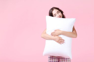Güzel kız beyaz yastık pembe arka plan holding
