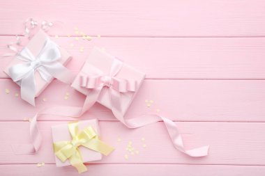 Şeritler ve pembe ahşap zemin üzerine konfeti ile hediye kutuları