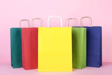 Pembe arka planda renkli kağıt alışveriş torbaları