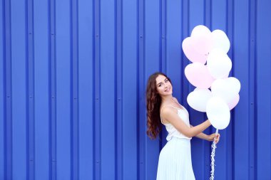 Mavi arka plan üzerinde duran Kalp balonlar ile şirin kız