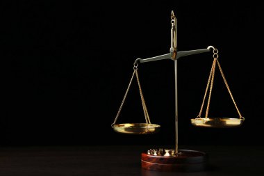 Koyu arka plan üzerinde ahşap masa üzerinde adaletin terazisi