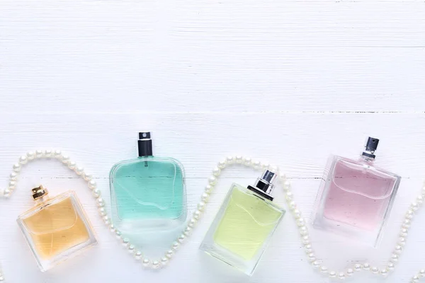 Botellas Perfume Colores Con Cuentas Sobre Fondo Madera Blanca —  Fotos de Stock