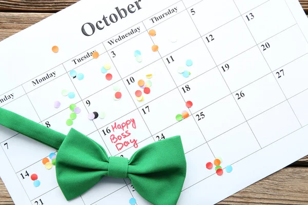 Inscription Happy Boss Day in calendar with bow tie and confetti