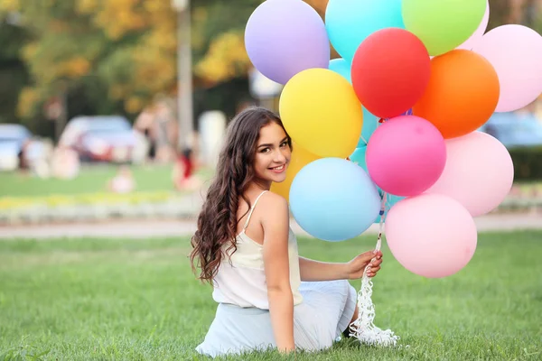 Vacker Flicka Med Färgade Ballonger Sitter Gräset Parken — Stockfoto