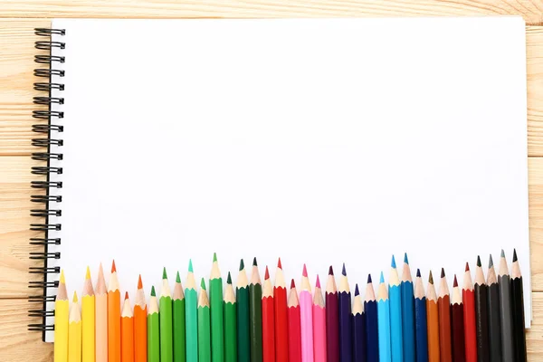 Crayons Couleur Dans Une Rangée Avec Carnet Sur Fond Bois — Photo