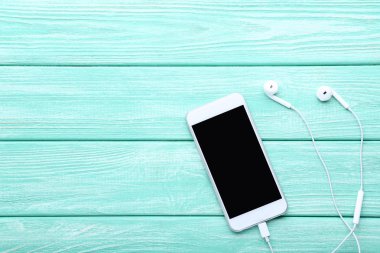 Mavi ahşap masa üzerinde kulaklık ile Smartphone