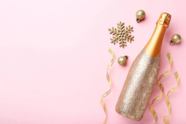 Pembe bir arka plan üzerinde Noel süslemeleri ile şampanya şişesi