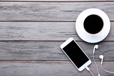 Kulaklık ve ahşap masa üzerinde kahve ile Smartphone