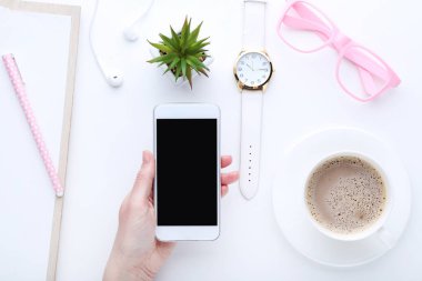 Kadın elinde fincan beyaz zemin üzerine kahve, gözlük ve Bilek seyretmek ile Smartphone