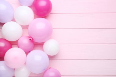 Pembe ahşap masa üzerinde renkli balonlar