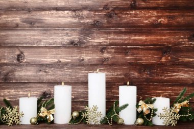 Köknar ağaç dalları ve kar taneleri kahverengi zemin üzerine beyaz Noel mumlar