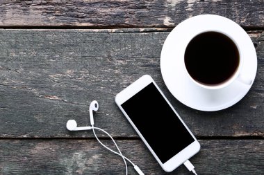 Kulaklık ve gri ahşap masa üzerinde kahve ile Smartphone