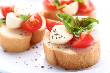 Bruschetta mozzarella peyniri, domates ve fesleğen yaprakları ile